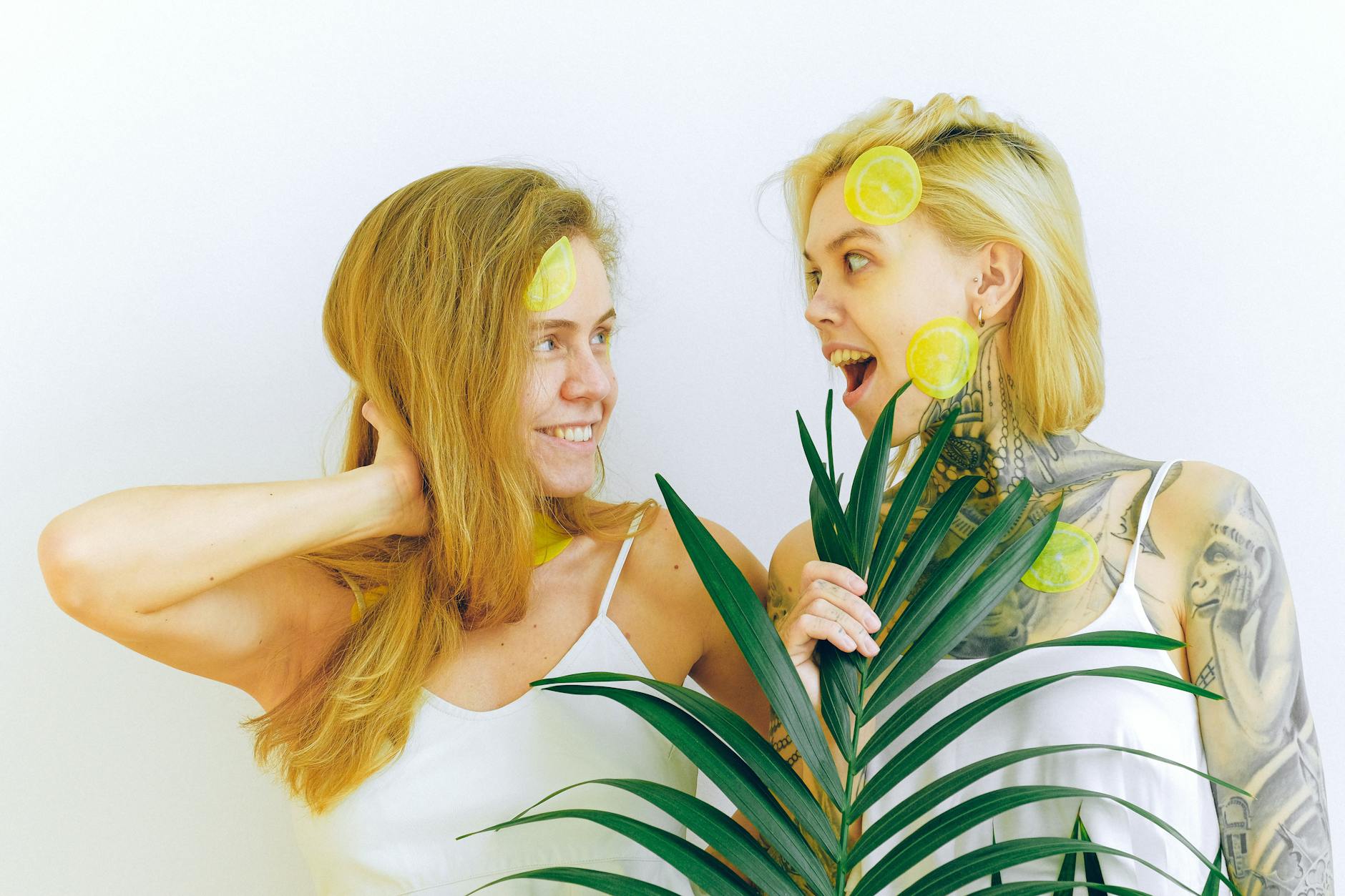 Two women smiling with lemon slices, expressing joy and comfort indoors