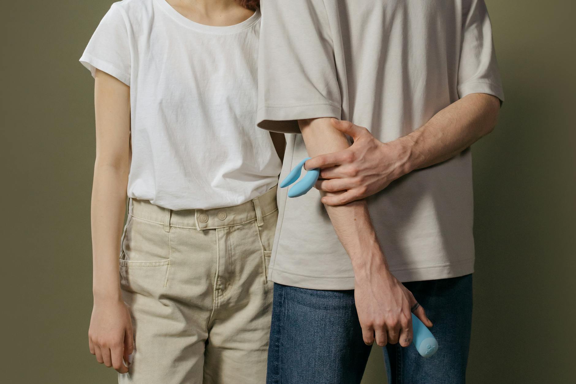 Person holding blue and pink silicone vibrators, examining options for sensitive skin